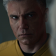 Pike, in his orange captain's uniform, stares intently at Nurse Chapel.